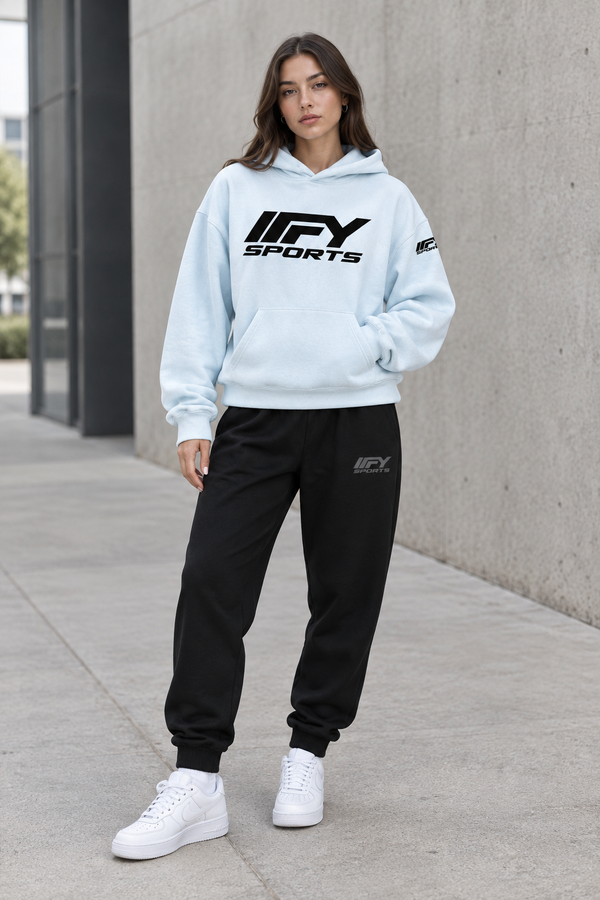 Female model wearing the pale-blue IFY hoodie and black cuffed joggers with Nike trainers