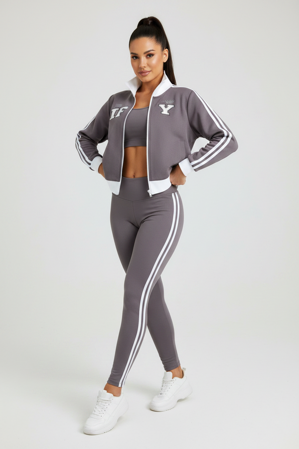 A dark gray track jacket with white accents, featuring a white stand collar, white sleeve stripes, a white front zipper, and white lettering on the chest.