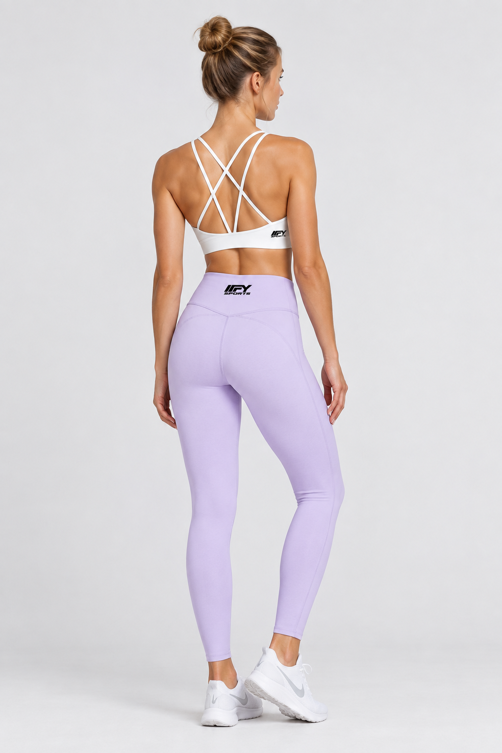 Female model back view wearing lavender IFY leggings and a white open-back cross-strap bra