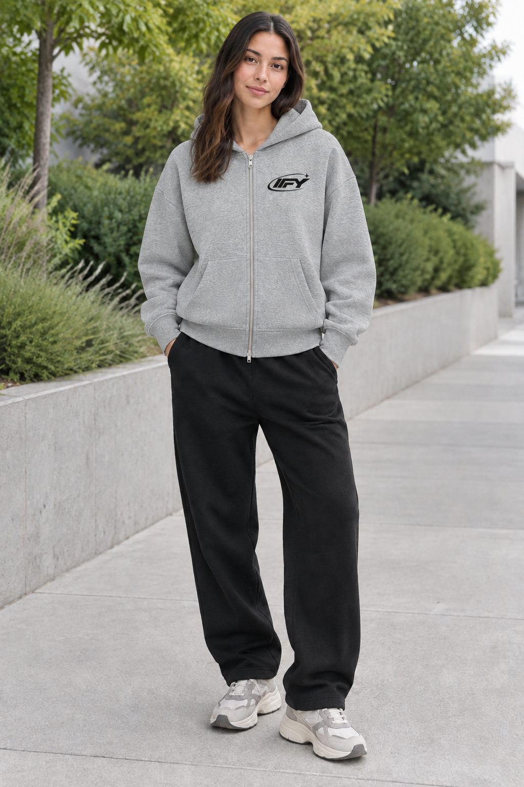 Female model wearing a heather-grey IFY zip hoodie and black sweatpants