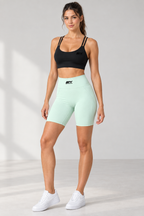 Female model wearing the black IFY sports bra and mint high-waisted shorts