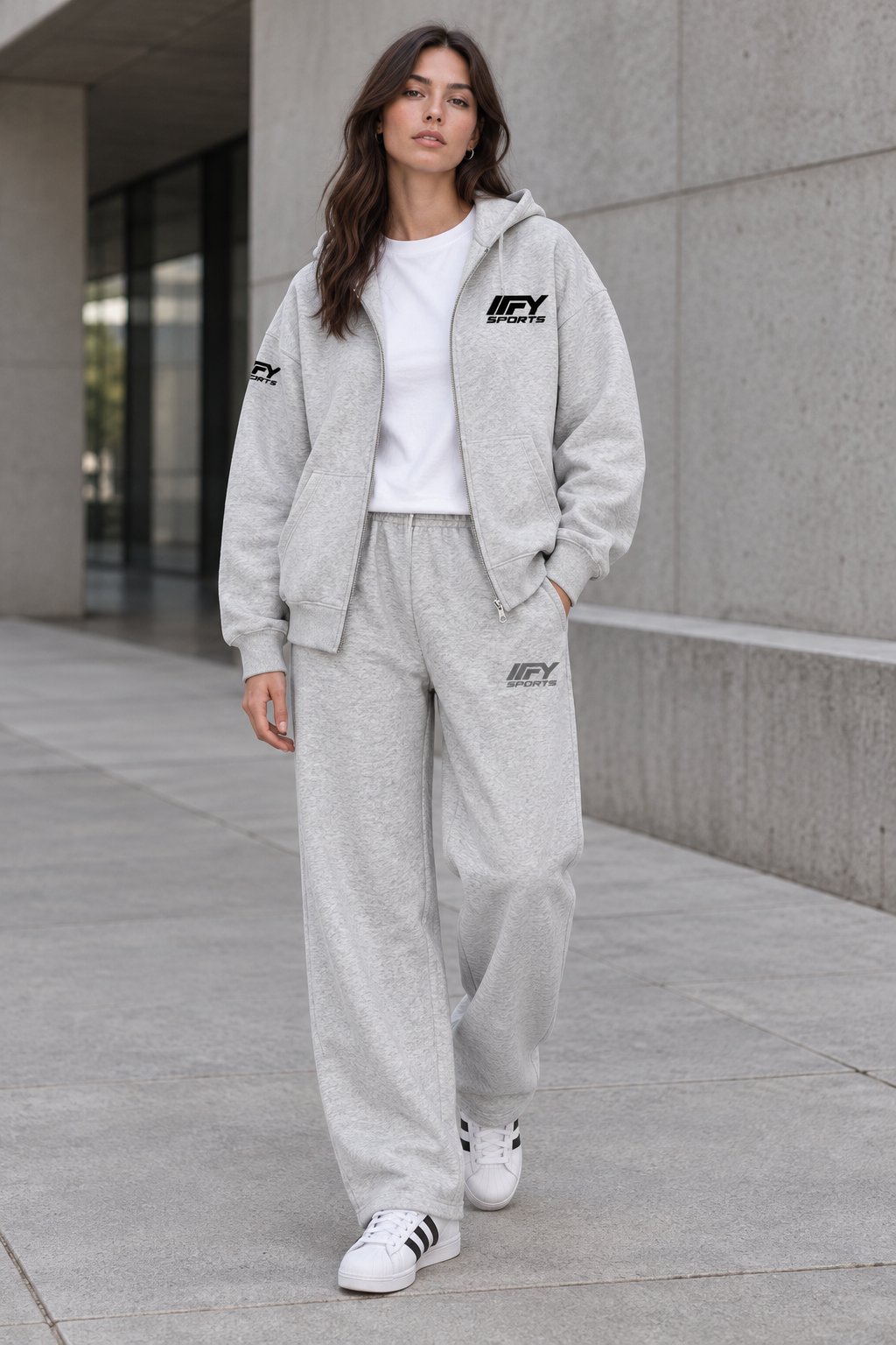 Female model wearing the grey IFY outfit with an open zip hoodie and Adidas trainers