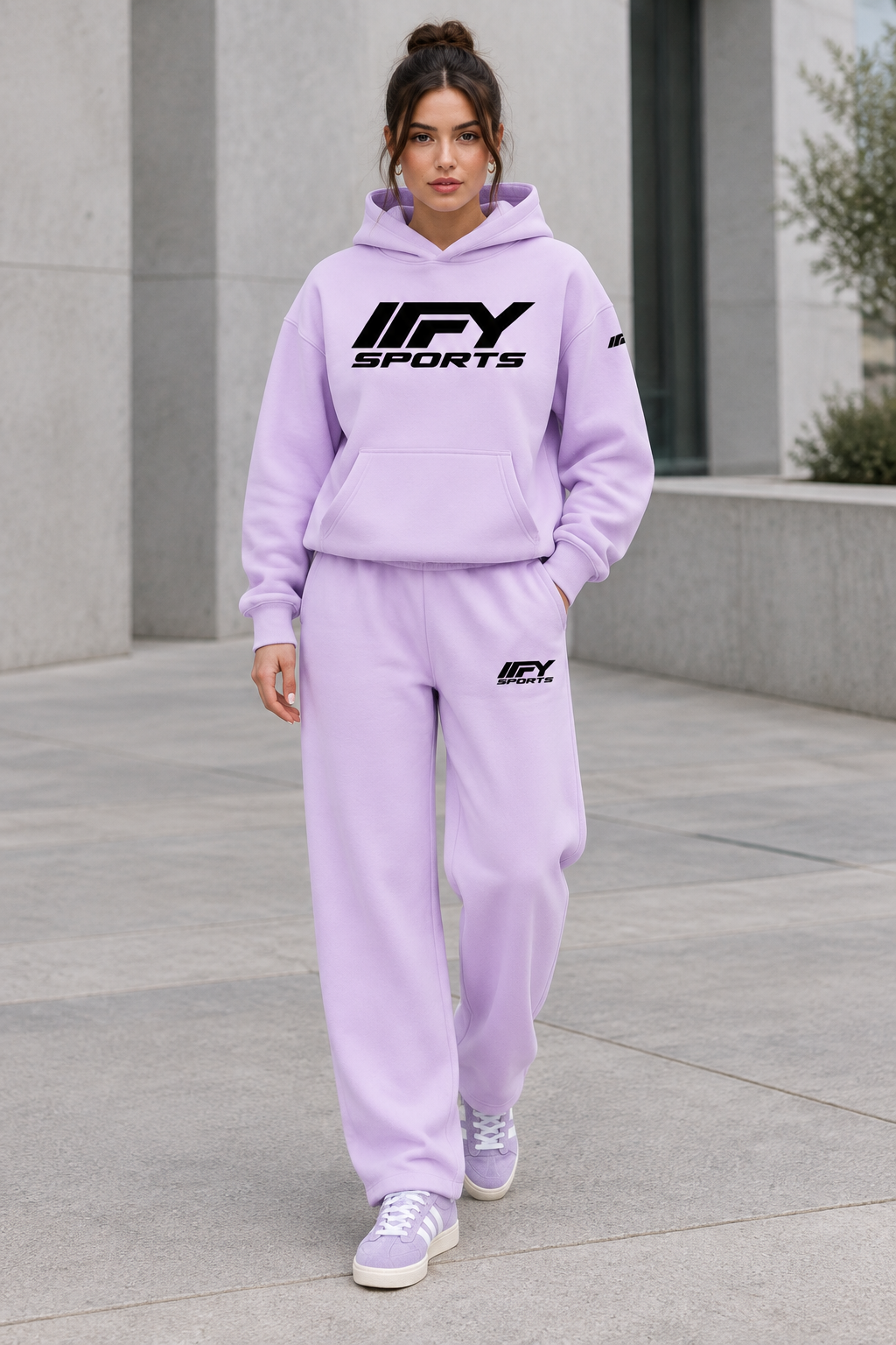 Female model wearing the lavender IFY hoodie and sweatpants set with Adidas Campus trainers