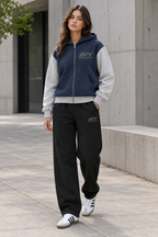 Female model wearing the navy-and-grey IFY zip hoodie and black sweatpants with Adidas trainers