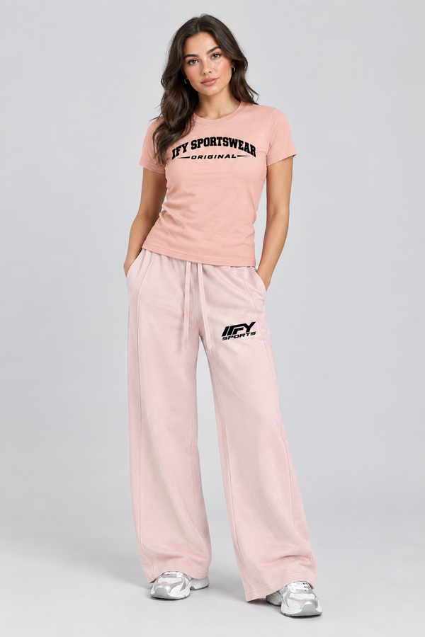 Female model wearing the pink IFY SPORTSWEAR ORIGINAL T-shirt and blush wide-leg IFY SPORTS trousers