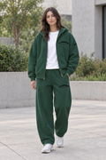 Female model wearing the unzipped green IFY hoodie over a white tee with matching barrel-leg sweatpants