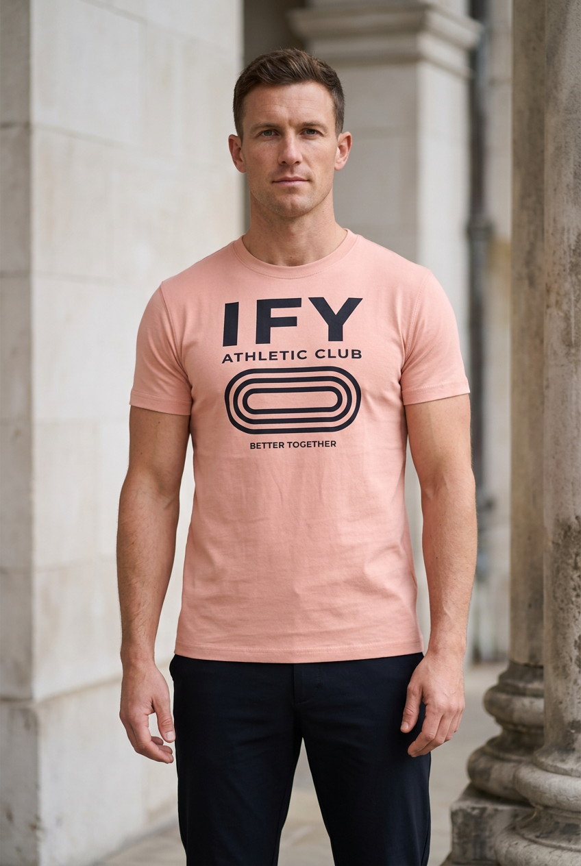 Male model wearing pink IFY unisex heavyweight slim-fit T-shirt with black Athletic Club front graphic