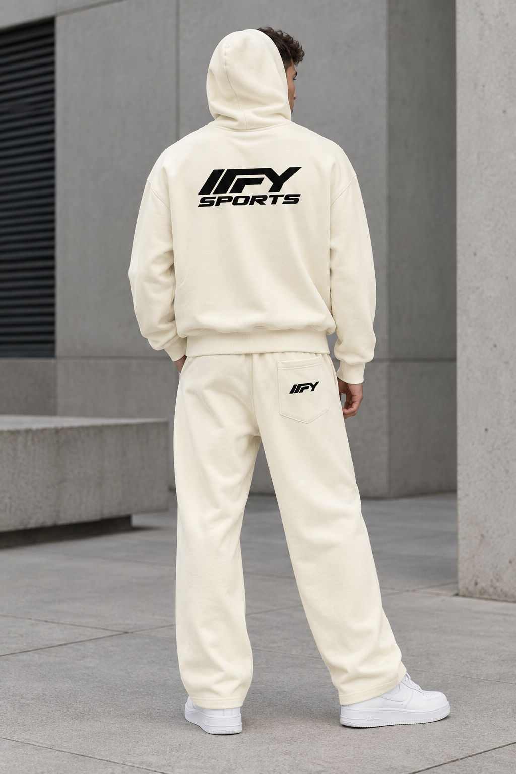 Male model back view wearing the cream IFY hoodie and wide-leg trousers with Nike trainers