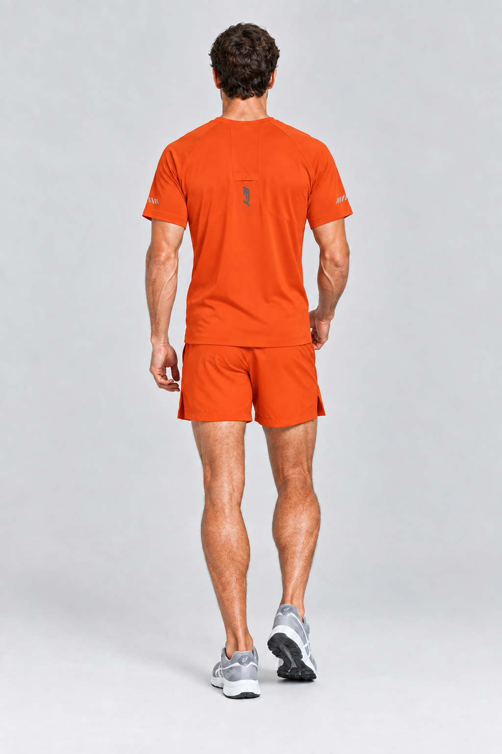 Male model back view wearing the orange IFY T-shirt, matching performance shorts and ASICS trainers