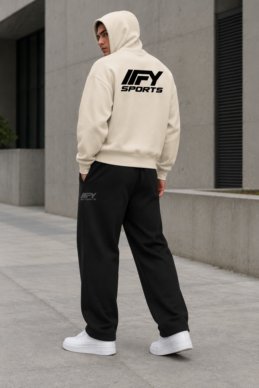 Male model with hood up showing the cream IFY hoodie’s back graphic, wearing black sweatpants and white Nike Air Force 1 trainers