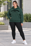 Plus-size female model wearing the green IFY hoodie with black leggings and white trainers in an outdoor streetwear pose