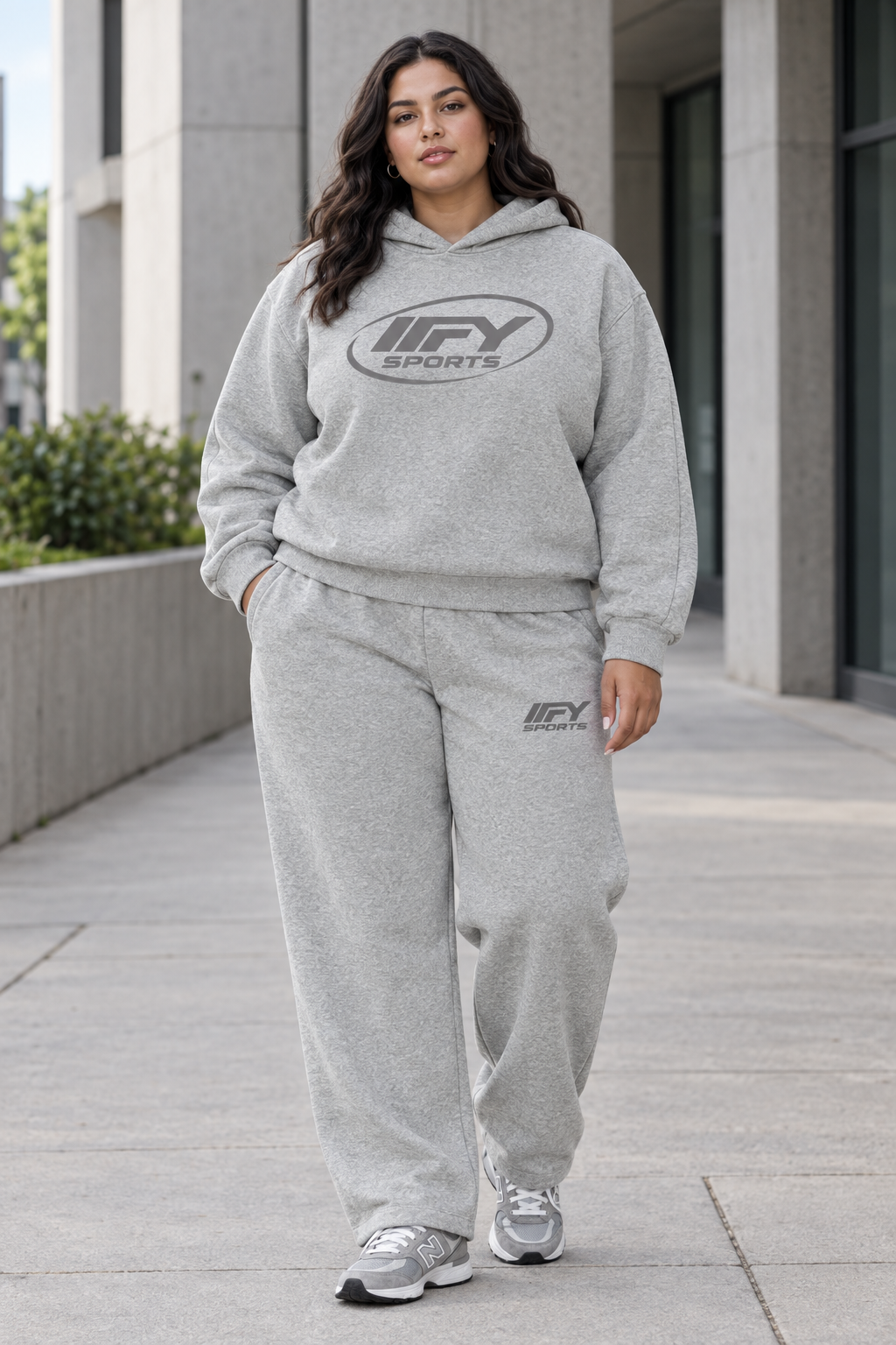 Plus-size female model wearing the grey IFY hoodie and sweatpants set with New Balance trainers