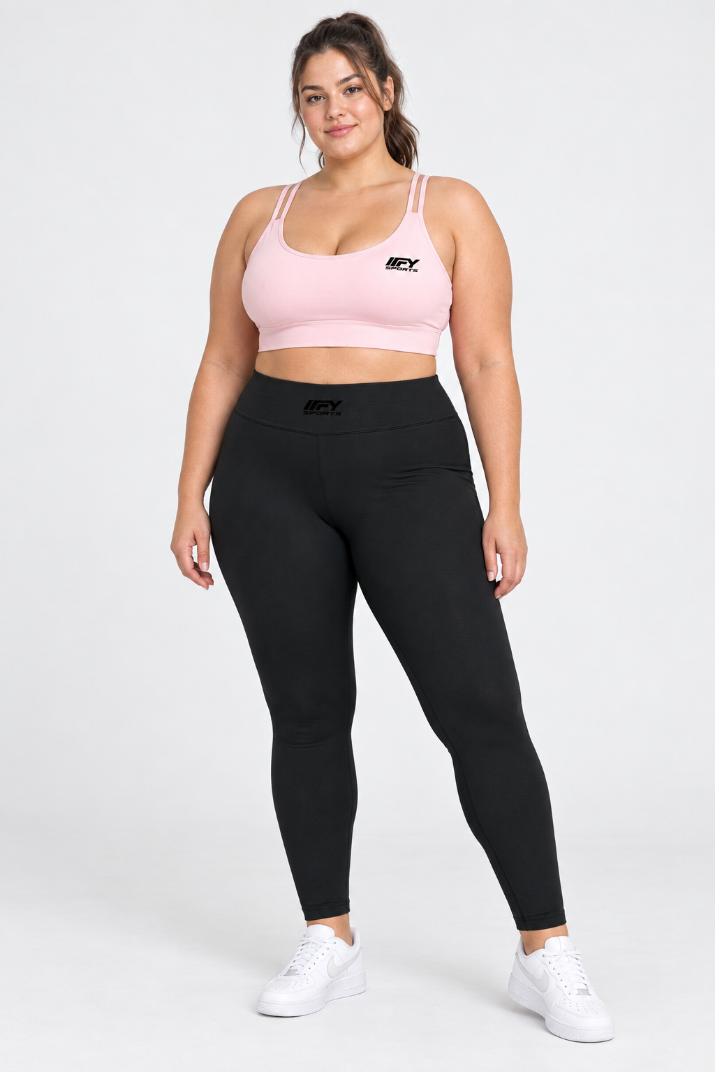 Plus-size female model wearing the pink IFY sports bra and black leggings